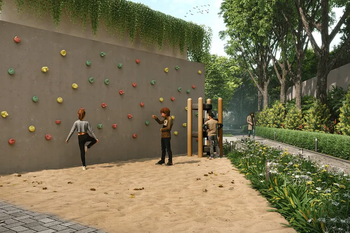 A rock-climbing wall beside a sand pit and gardens